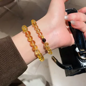 Detailed view of yellow citrine bead bracelet with agate flower charm on a woman's wrist
