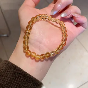 Macro view showing a citrine beaded bracelet on a person's wrist with warm amber tones.