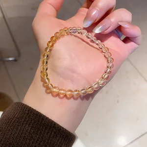 Detailed view of translucent yellow citrine agate beaded bracelet worn on a woman's wrist