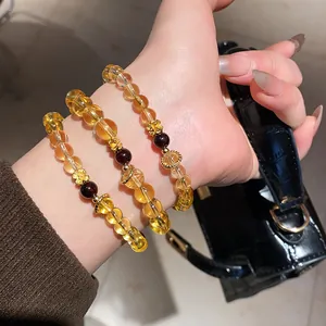 Close-up of citrine and agate beaded bracelets with golden flower charms on wrist