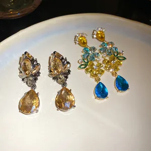 Primer plano de elegantes pendientes florales de cristal con colgantes azules y champán