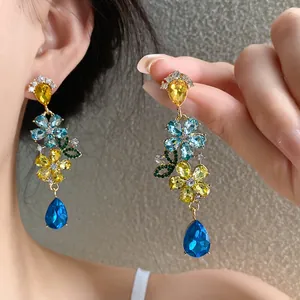Detalle de elegantes pendientes de flores de cristal con borlas azules y amarillas