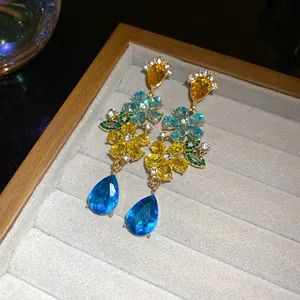 Primer plano de pendientes florales con cristales brillantes en azul y amarillo.
