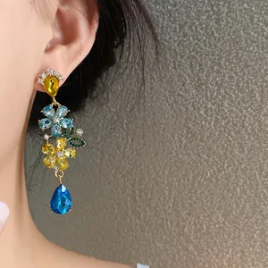 Primer plano de elegantes pendientes colgantes de flores y lágrima con gemas brillantes