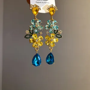 Primer plano de pendientes de flores con cristales de gota amarillos y azules.