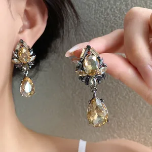Detalle de pendientes de cristal lágrima champán con elegante engaste floral de diamantes.