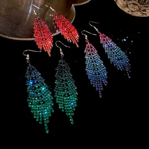 Stunning colorful rhinestone feather tassel earrings presented on a dark surface