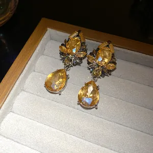 Detalle de pendientes de lujo con flores de diamantes amarillos y cristales de gota