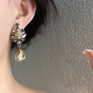 Detalle de pendiente con cristal champán en forma de gota y diseño floral vintage