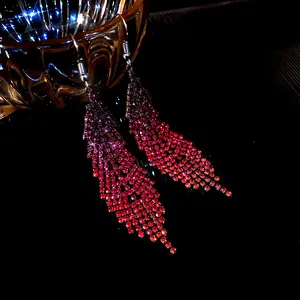 Detailed macro view of sparkling red rhinestone feather tassel dangling earrings