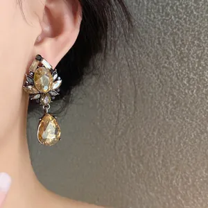 Detalle de elegantes pendientes de flor y gota de agua en cristal ámbar puestos en la oreja