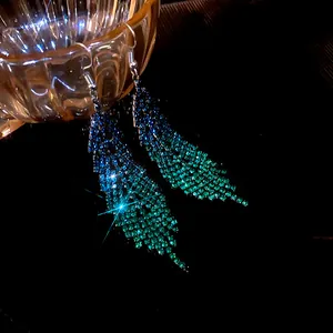 Close-up view of sparkling rhinestone feather tassel earrings with blue-green gradient