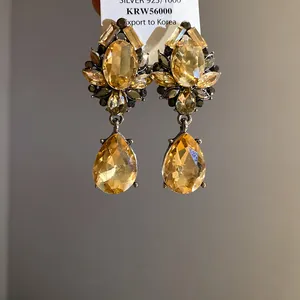 Primer plano de elegantes pendientes de cristal ámbar con aguja de plata 925