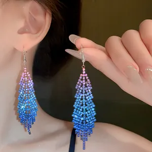 Detail view of shimmering gradient purple and blue rhinestone fringe earrings on a model