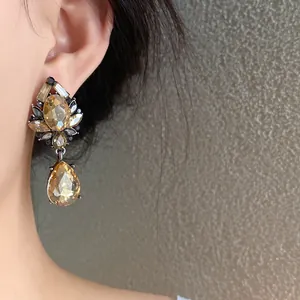 Primer plano detallado de pendientes de gota de cristal champán con diseño de flores