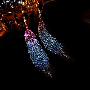 Macro view of sparkling rhinestone feather earrings featuring a blue-pink gradient