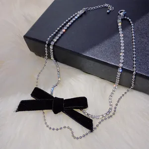 Détail d'un collier double épaisseur avec nœud en velours noir et strass brillants