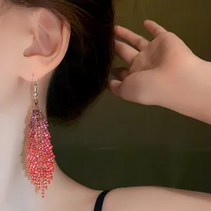 Close-up detail of sparkling pink and red rhinestone tassel earrings worn by a model