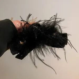 Dettaglio di una pinza per capelli nera con strass e piume eleganti.