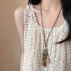 Long collier ethnique bohème avec pendentif fleuri et glands beiges porté par un mannequin