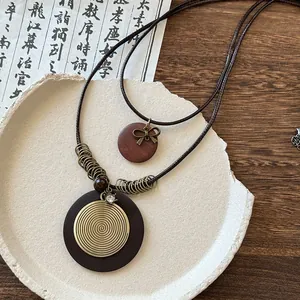 Gros plan d'un long collier de style Zen néo-chinois avec un pendentif en métal doré