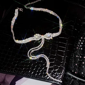 Ras de cou étincelant avec nœud en strass et longs glands sur fond noir texturé.