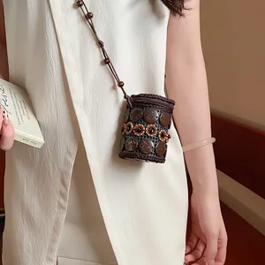 Detail view of a bohemian cylindrical necklace pouch made of brown coconut shells.