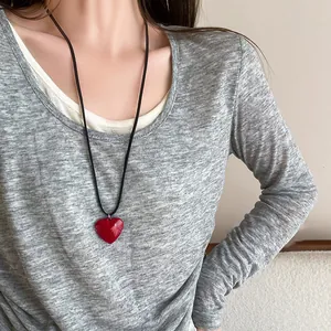 Vue rapprochée d'un collier long à cordon noir avec un pendentif en forme de cœur rouge