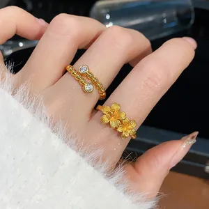 Primo piano di anelli regolabili placcati in oro con fiori e zirconi sulla mano femminile