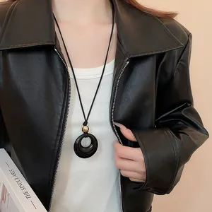 Collier long minimaliste de style zen avec un pendentif anneau noir et perle dorée