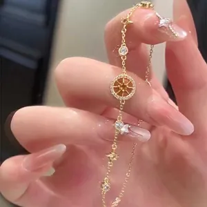 Vue détaillée d'un bracelet doré avec étoile à huit branches en zircon et boussole