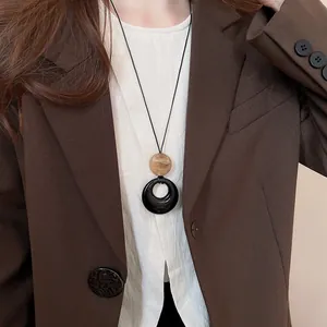 Détail du collier long de style Zen avec pendentifs circulaires en résine noire.