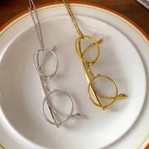 Stylish metal eyeglasses pendant necklace in gold and silver on a minimalist plate
