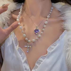 Zoom sur un collier double couche avec cristal cœur violet et pendentif croix