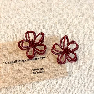 Detailed macro view of vintage hollow red flower stud earrings on natural linen cloth