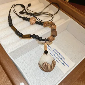 Gros plan sur un collier Zen avec un pendentif en bouton de lotus dans un coffret en bois