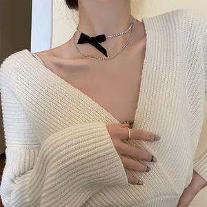 Élégant collier ras du cou à double couche avec un nœud noir et des strass brillants.