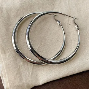 Grandi orecchini a cerchio in argento minimalisti con finitura lucida e superficie liscia.
