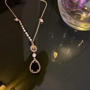 Gros plan sur un collier en or vintage avec perles et pendentif goutte d'eau noire