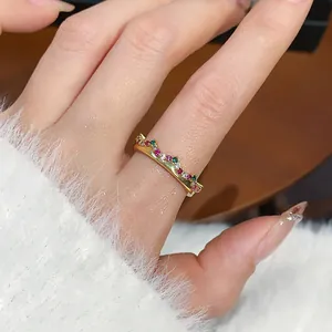Elegante anello a corona placcato oro con gemme colorate indossato sul dito