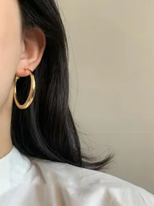Primo piano di un orecchino a cerchio in oro liscio minimalista indossato da un modello