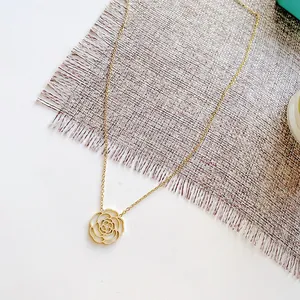 Vue détaillée d'un élégant collier avec pendentif fleur de camélia doré sur un tapis
