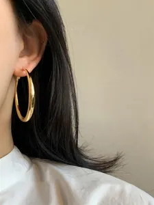 Primo piano di un grande orecchino a cerchio in oro lucido indossato da una modella
