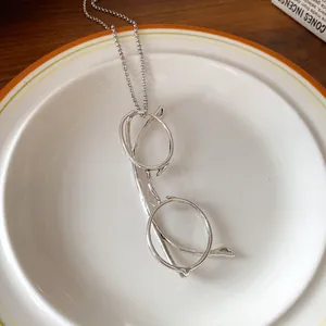 Detailed view of a unique silver metal glasses pendant on a minimalist chain necklace