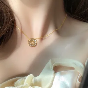 Détail d'un collier en chaîne dorée délicate avec un pendentif fleur de camélia blanc