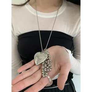 Detalle del collar con colgante de corazón plateado con borlas de cuentas y texto