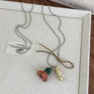 Detalle de collar de cadena de bolas con colgante de cacahuete y borla de colores