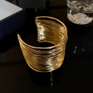Detail shot of wide multi-layer gold wire cuff bracelet with a modern designer aesthetic.