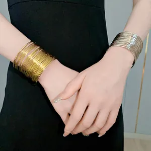 Detailed view of trendy multilayer gold and silver metal wire bangles on model's wrists.