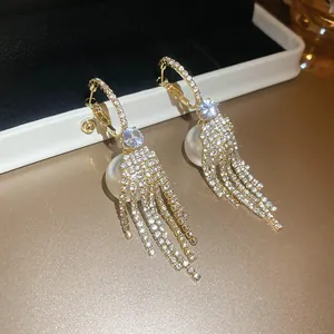 Elegant gold hoop earrings featuring white pearls and long sparkling rhinestone tassels